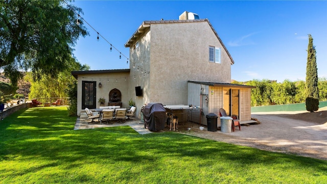 rear view of house with a lawn, a patio area, and exterior fireplace