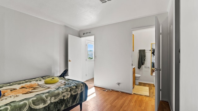 bedroom with ensuite bath, a textured ceiling, and hardwood / wood-style flooring