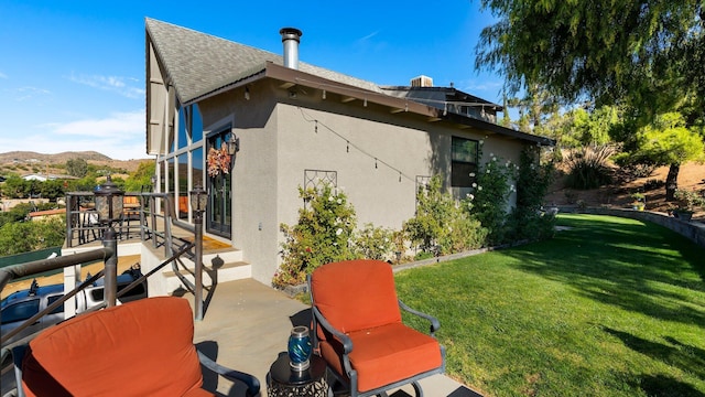 rear view of property with a mountain view, a patio area, and a yard