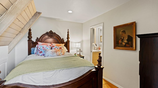 bedroom with ensuite bathroom and light hardwood / wood-style flooring