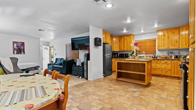 kitchen featuring a center island, light stone counters, a textured ceiling, and appliances with stainless steel finishes