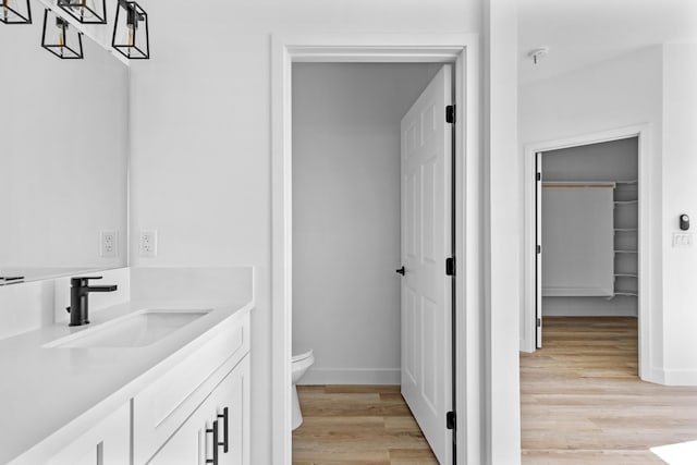 bathroom with hardwood / wood-style floors, vanity, and toilet