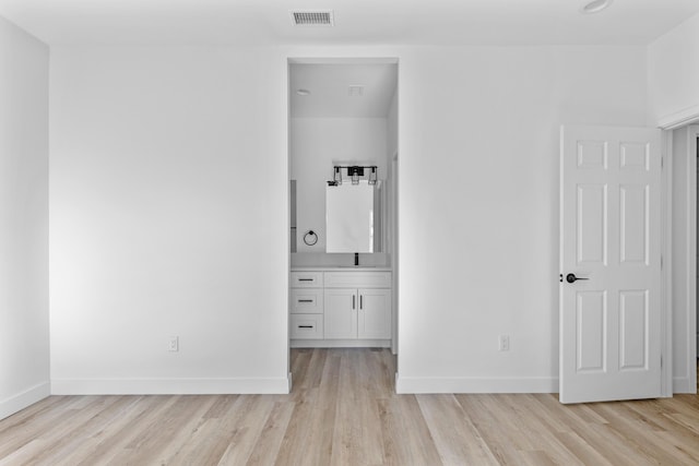 unfurnished bedroom with ensuite bath, sink, and light wood-type flooring