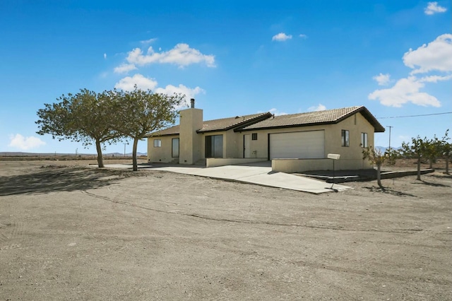 single story home featuring a tile roof, a chimney, stucco siding, concrete driveway, and an attached garage