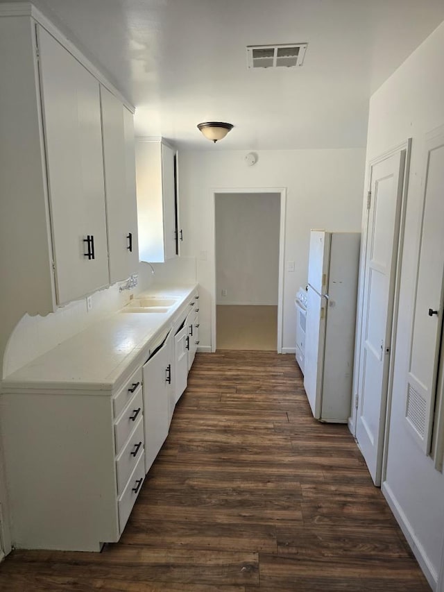 kitchen featuring white appliances, white cabinetry, dark wood-type flooring, and sink