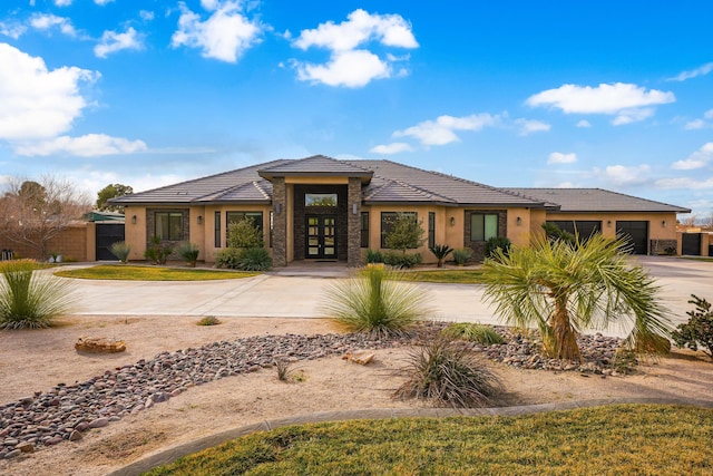 prairie-style home with french doors, a tile roof, stucco siding, concrete driveway, and a garage