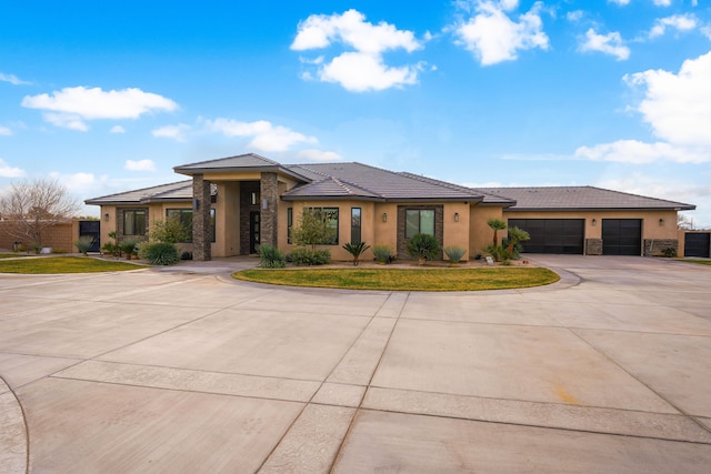 prairie-style house with a garage, concrete driveway, stone siding, and stucco siding