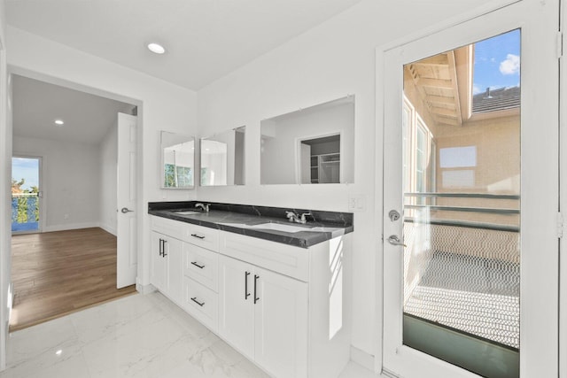 bathroom featuring a sink, baseboards, double vanity, and marble finish floor