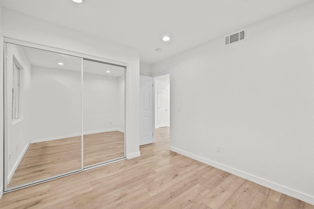 unfurnished bedroom with visible vents, a closet, wood finished floors, baseboards, and recessed lighting
