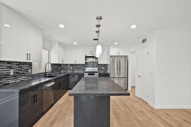 kitchen featuring visible vents, a kitchen island, a sink, light wood-style flooring, and appliances with stainless steel finishes