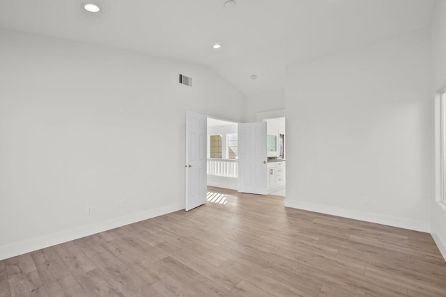 spare room with visible vents, baseboards, lofted ceiling, and light wood-type flooring