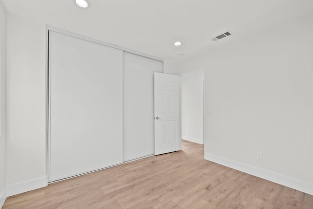 unfurnished bedroom with visible vents, a closet, baseboards, light wood-style floors, and recessed lighting