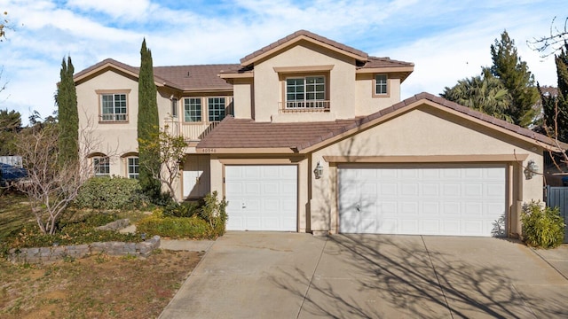 traditional-style house with an attached garage, driveway, a tile roof, and stucco siding