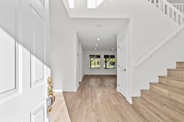entrance foyer featuring recessed lighting, light wood-style flooring, stairs, and baseboards