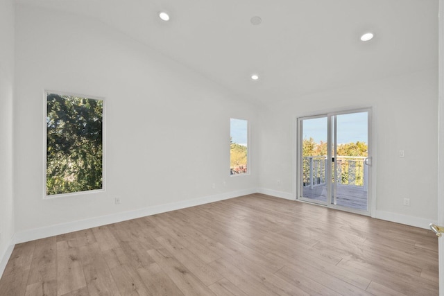 unfurnished room with baseboards, vaulted ceiling, a healthy amount of sunlight, and wood finished floors