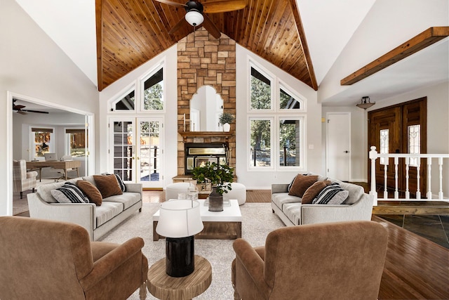 living room with wood-type flooring, a stone fireplace, plenty of natural light, and high vaulted ceiling