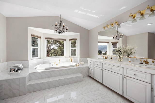 bathroom with an inviting chandelier, lofted ceiling, tiled bath, and vanity