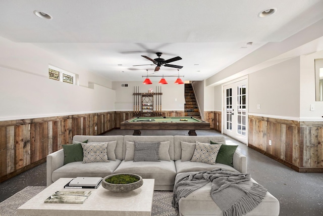 living room with wooden walls, billiards, french doors, and ceiling fan