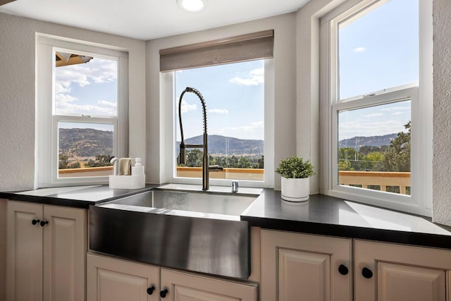 kitchen with white cabinetry, a mountain view, and sink