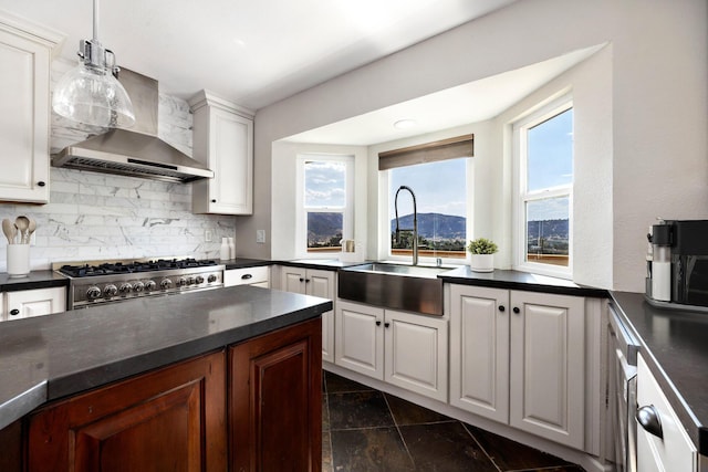 kitchen featuring sink, white cabinets, stove, a mountain view, and wall chimney exhaust hood