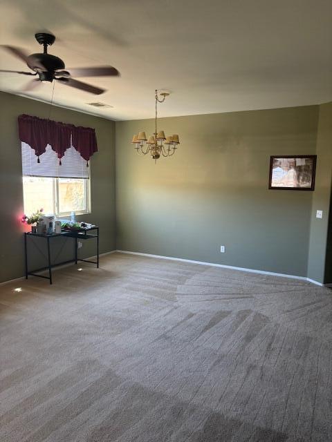 carpeted spare room with ceiling fan with notable chandelier