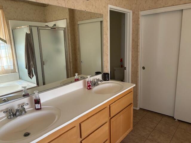 bathroom featuring tile patterned flooring, vanity, and an enclosed shower