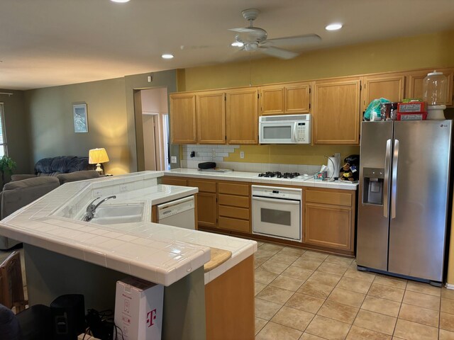 kitchen featuring ceiling fan, tile counters, sink, white appliances, and light tile patterned flooring