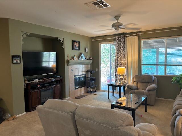 living room with ceiling fan, a fireplace, and light carpet