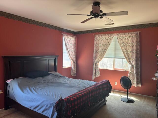 carpeted bedroom with multiple windows and ceiling fan