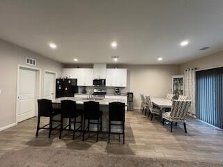 kitchen with white cabinetry, appliances with stainless steel finishes, a breakfast bar, and light wood-type flooring