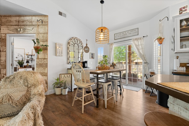dining space featuring wood finished floors and high vaulted ceiling