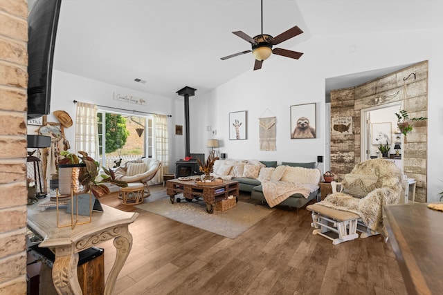 living room with a wood stove, wood finished floors, a ceiling fan, and high vaulted ceiling