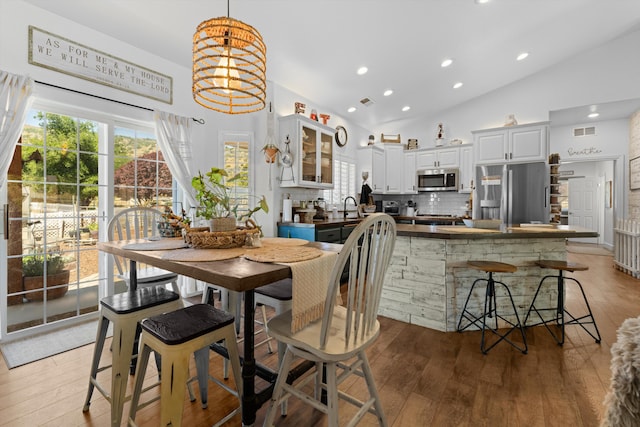 dining area featuring high vaulted ceiling, wood finished floors, recessed lighting, and a chandelier