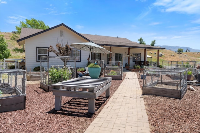 rear view of house featuring a vegetable garden, a mountain view, and a shingled roof