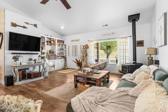 living area featuring a wood stove, vaulted ceiling, ceiling fan, wood finished floors, and recessed lighting