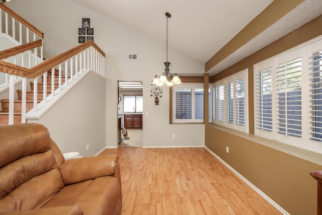 living room featuring light wood-type flooring, an inviting chandelier, and lofted ceiling