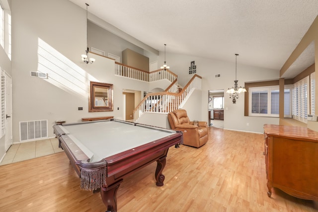 recreation room with light hardwood / wood-style floors, a towering ceiling, a chandelier, and pool table