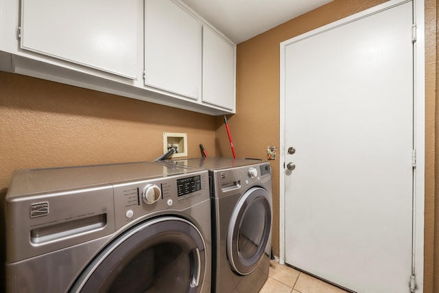 washroom featuring cabinets, light tile patterned floors, and washer and clothes dryer