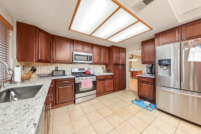 kitchen with light tile patterned flooring, sink, light stone countertops, and stainless steel appliances