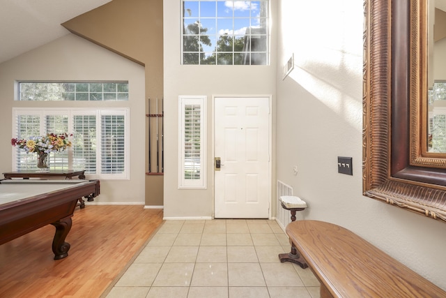 tiled entrance foyer featuring a towering ceiling, plenty of natural light, and pool table