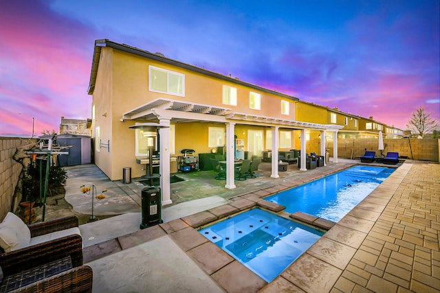 back of house featuring a fenced backyard, a pool with connected hot tub, a patio, and stucco siding