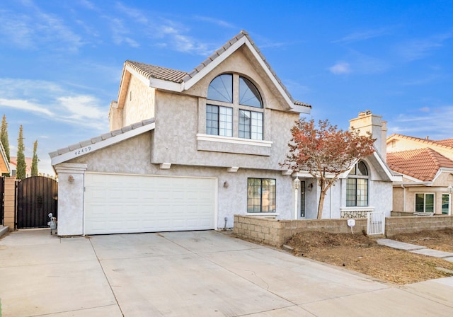 view of front of house featuring concrete driveway, a gate, and stucco siding