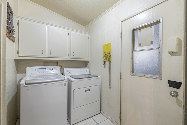 laundry room with cabinets, ornamental molding, a textured ceiling, washer and clothes dryer, and light tile patterned floors