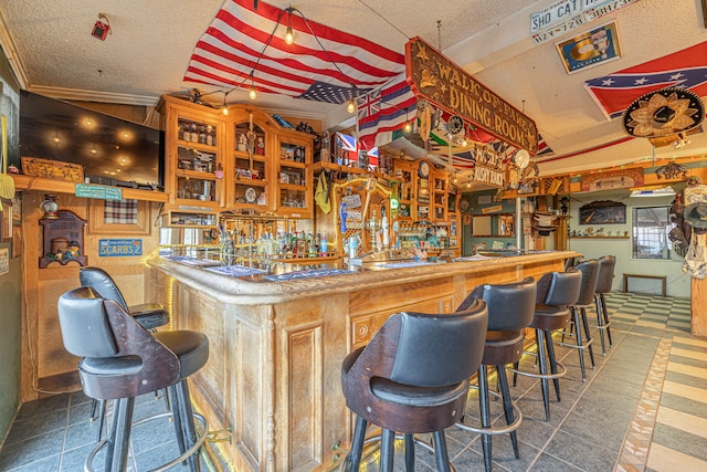 bar featuring lofted ceiling, ornamental molding, and a textured ceiling