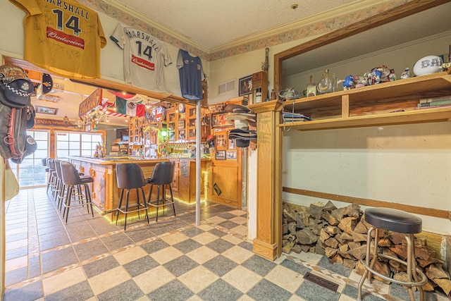 interior space with a breakfast bar, ornamental molding, and a textured ceiling