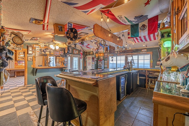 kitchen featuring wine cooler, ceiling fan, a textured ceiling, kitchen peninsula, and a breakfast bar area