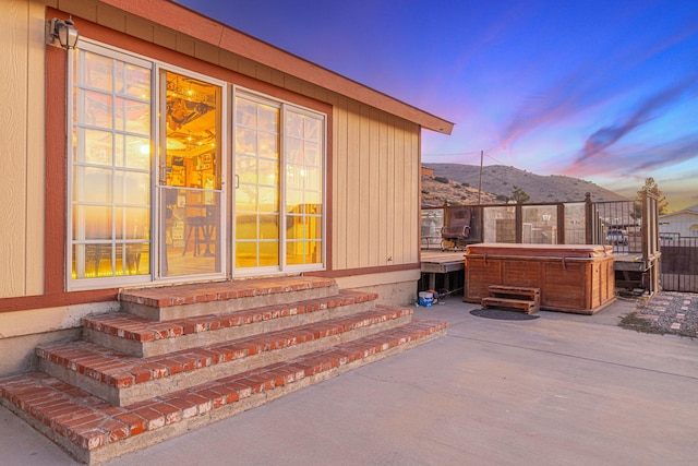 patio terrace at dusk with a mountain view and a hot tub