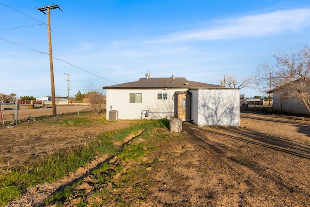 back of house with central air condition unit, fence, and stucco siding