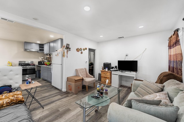 living area with wood finished floors, visible vents, and recessed lighting