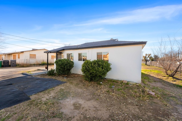 view of side of property with fence and stucco siding